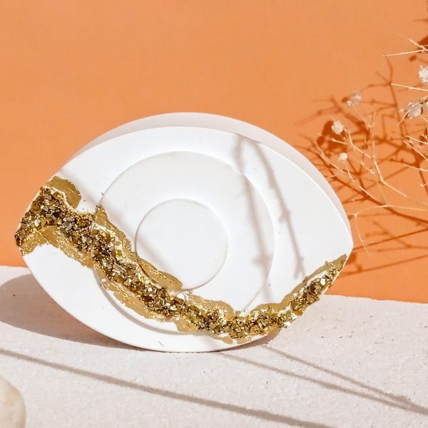 Πολυτελές και συμβολικό, το Magma Touch αποτυπώνει την αυθεντική αισθητική του καλοκαιρινού  Ήλιου και των Ελληνικών νησιών μέσα από τη δύναμη της απλότητας. Ένα χειροποίητο κεραμικό μάτι, εμπνευσμένο από το ελληνικό φως και το παραδοσιακό φυλαχτό της καλής τύχης.